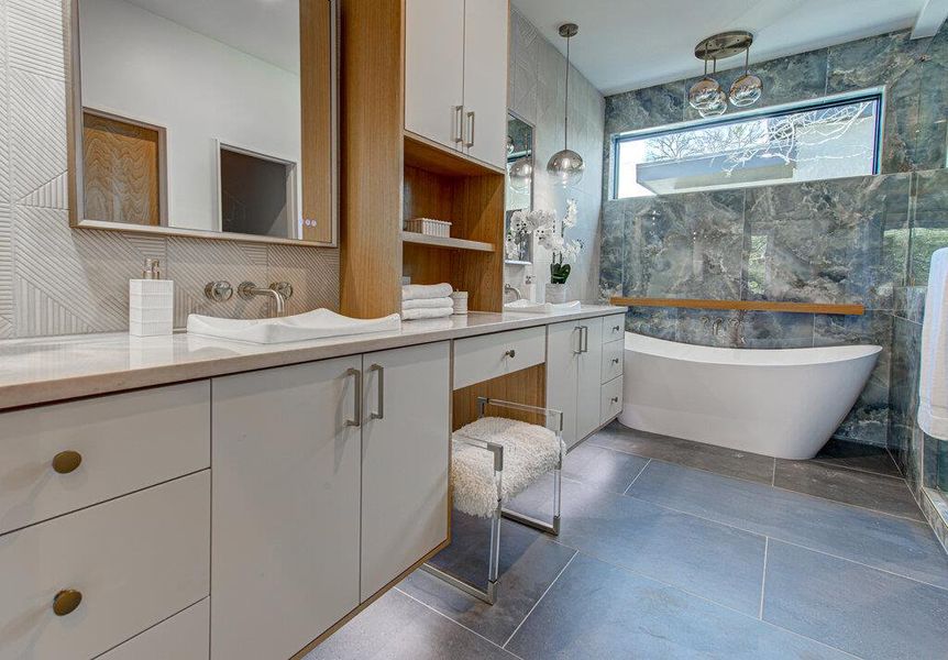 Full bath featuring double vanity, a freestanding tub, and tile walls