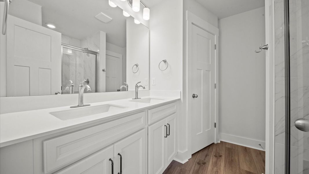 Notable primary bath featuring dual vanity, tiled walk-in shower, and tasteful design touches throughout