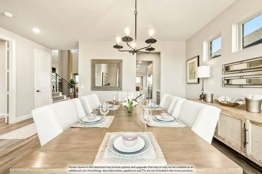 Dining room with long wood table, white chairs, chandelier, and hardwood floors