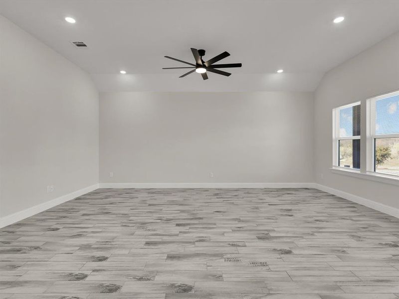 Empty room featuring ceiling fan and lofted ceiling