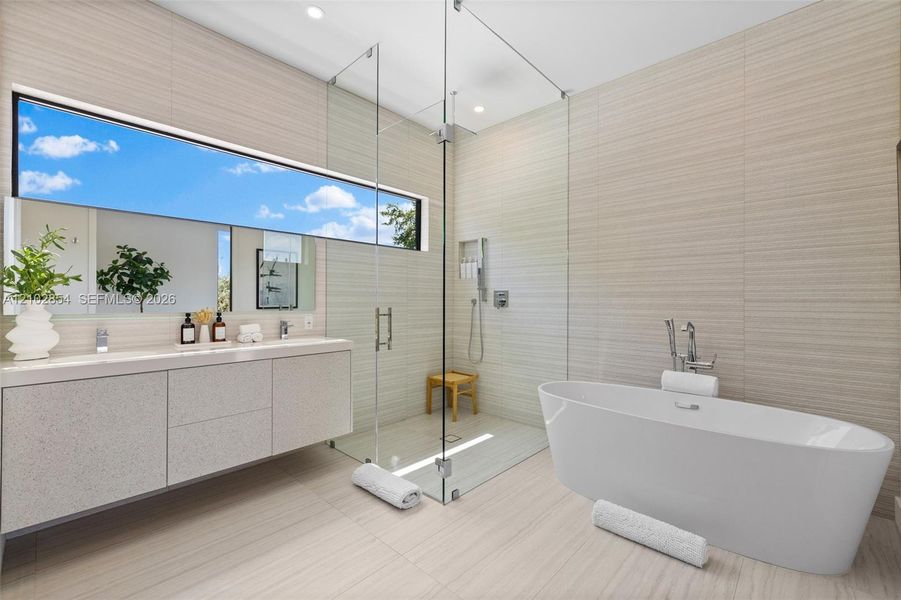Floating vanity with a light-toned finish, freestanding soaking tub, glass-enclosed walk-in shower with integrated shelving, and horizontal wall tile extending from floor to ceiling