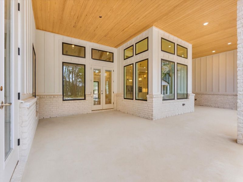 Expansive back porch with soaring wood-lined ceilings, elegant architectural detail, and seamless indoor-outdoor flow—enjoy the fully equipped outdoor kitchen for luxe entertaining.