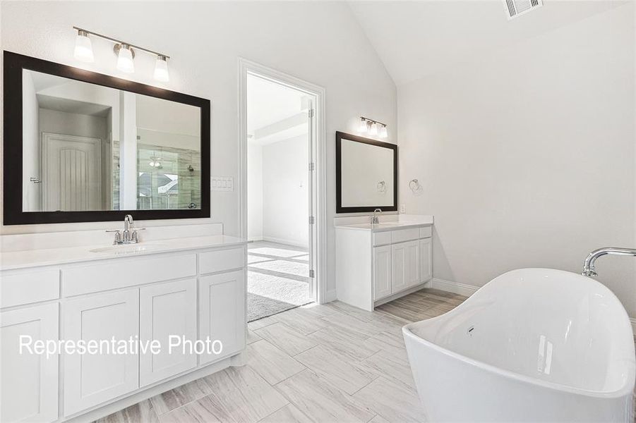 Bathroom featuring tile patterned flooring, vaulted ceiling, plus walk in shower, and vanity