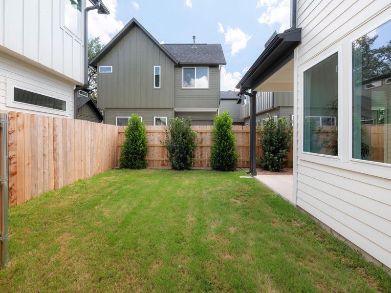 A verdant backyard retreat enclosed by a wooden privacy fence, offering a perfect green escape.