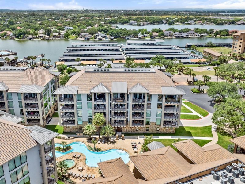 Multi-story residential complex featuring private balconies, stone and stucco exterior, and a central courtyard with a resort-style pool Multi-story residential complex featuring private balconies, stone and stucco exterior, and a central courtyard with a resort-style pool