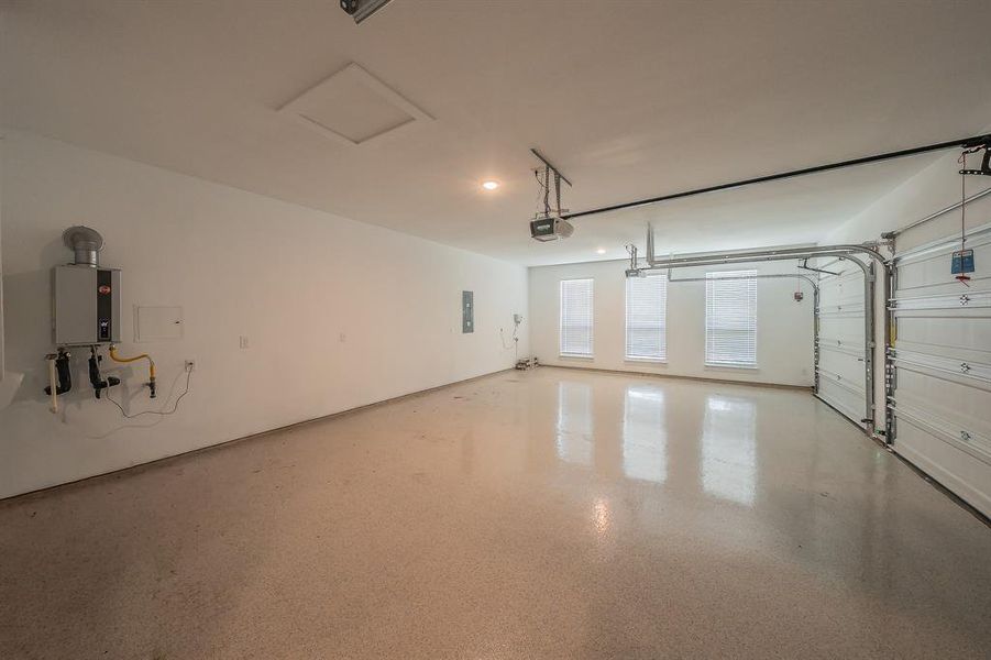 Spacious garage featuring an epoxy floor, three windows with blinds, and an overhead garage door