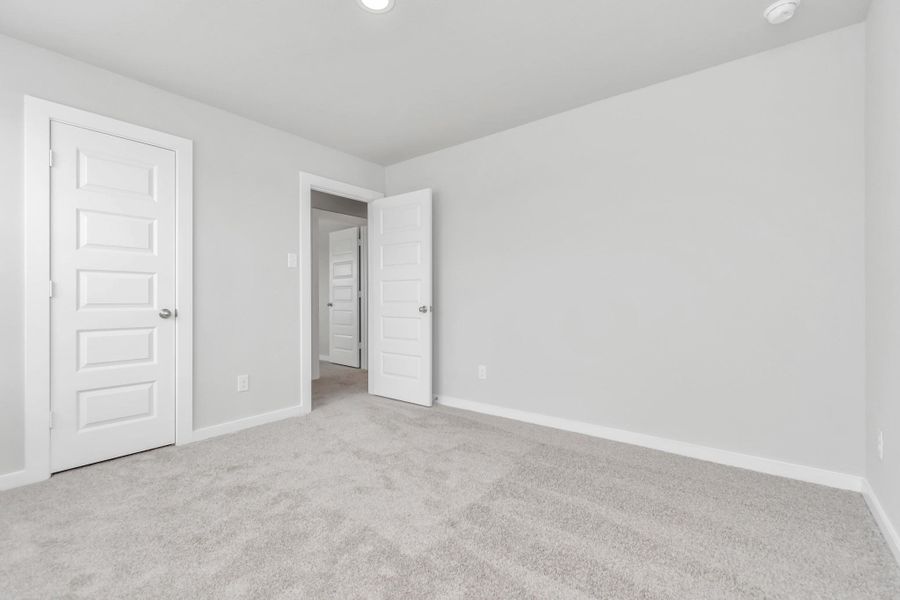 generously sized secondary bedrooms, showcasing 5-panel doors with modern hardware, large windows adorned with privacy blinds, and spacious closets boasting sleek and contemporary finishes. Sample photo of completed home with similar floor plan. Actual colors and selections may vary.