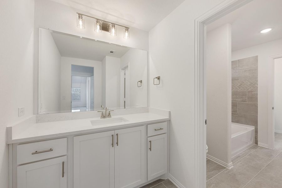 Bathroom with white vanity, large mirror, and separate room with soaking tub and tile shower Bathroom with white vanity, large mirror, and separate room with soaking tub and tile shower