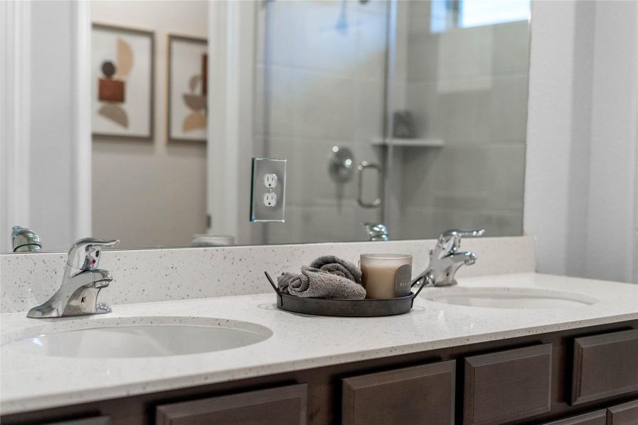 Enjoy a highly functional en-suite with a wide double vanity, set against rich espresso shaker-style cabinetry and a full-width mirror with outlet access.