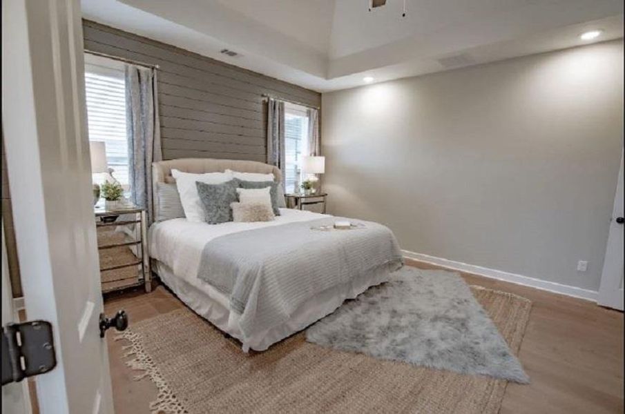 Spacious room featuring a tray ceiling with recessed lighting, shiplap accent wall, wood-finish flooring, and white trim