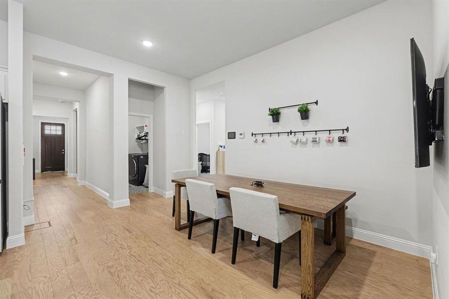 Open concept living area featuring wood-finish flooring, recessed lighting, and a dedicated laundry closet with patterned tile flooring