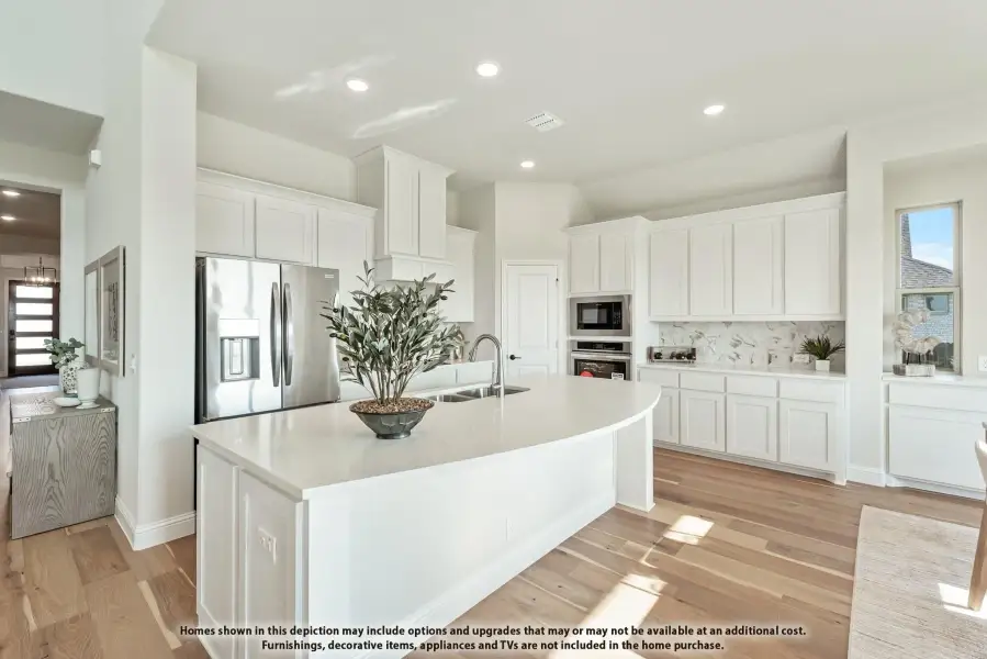 White kitchen with large center island, stainless steel appliances, and light hardwood floors White kitchen with large center island, stainless steel appliances, and light hardwood floors