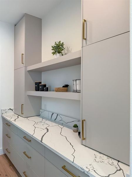 Kitchen with modern cabinets, light wood-type flooring, gray cabinets, light stone countertops, and open shelves Kitchen with modern cabinets, light wood-type flooring, gray cabinets, light stone countertops, and open shelves