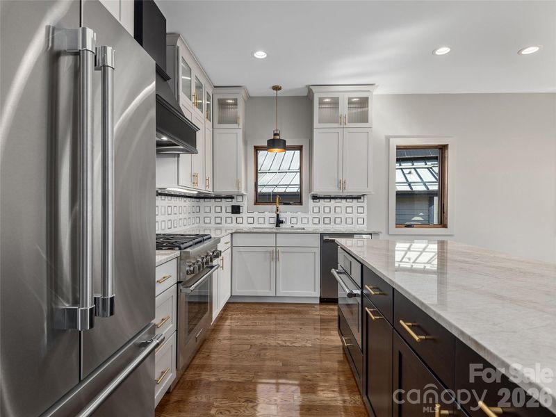 Another view of the designer kitchen showcasing granite countertops, Thermador appliances, Wolf Home Products cabinetry, tile backsplash, and an oversized center island.