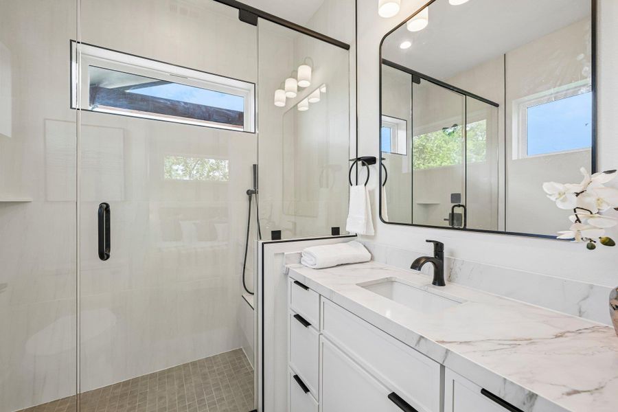 A contemporary bathroom with a bench, shower wand, and a spacious glass-enclosed shower alongside a vanity with plenty of drawers for storage. A contemporary bathroom with a bench, shower wand, and a spacious glass-enclosed shower alongside a vanity with plenty of drawers for storage.