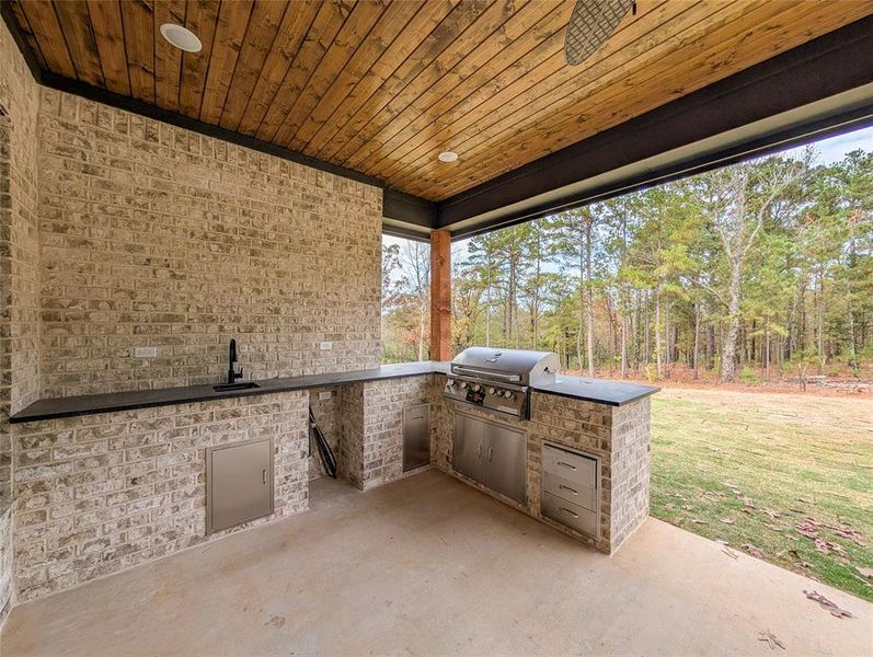 View of patio featuring exterior kitchen and a sink