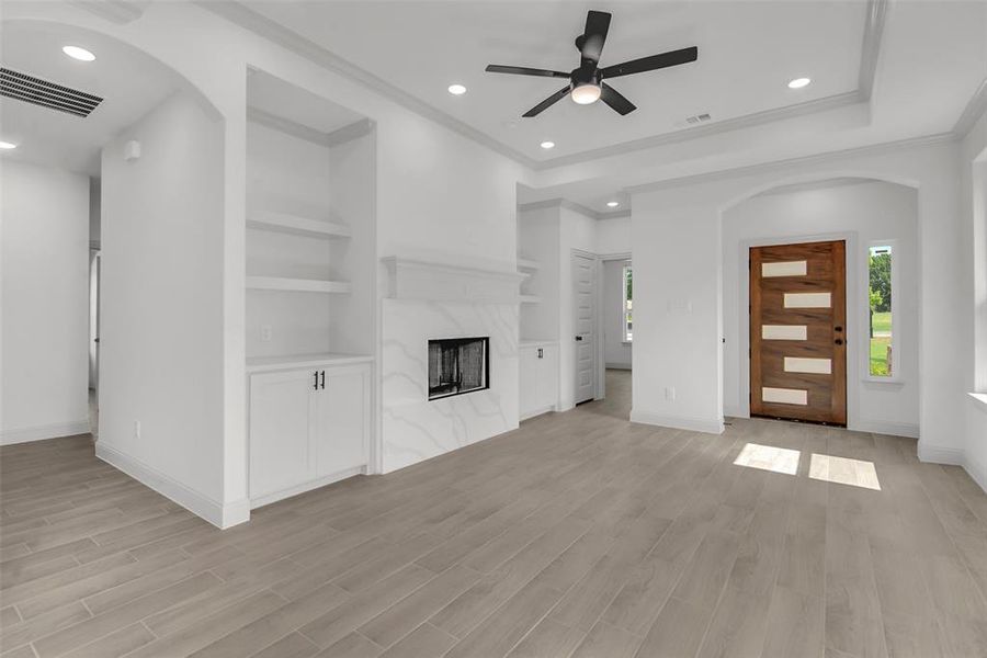 Unfurnished living room featuring healthy amount of natural light, a ceiling fan, recessed lighting, arched walkways, and ornamental molding Unfurnished living room featuring healthy amount of natural light, a ceiling fan, recessed lighting, arched walkways, and ornamental molding