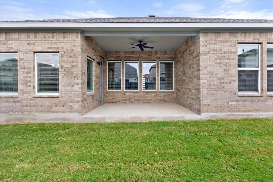Back of house featuring ceiling fan, brick siding, a patio, and a yard