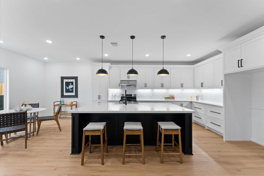 A picture-perfect island kitchen features a breakfast bar under mounted lights. Photo is of similar kitchen.