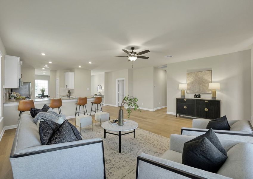 Open-concept living room featuring sofas, a coffee table, an area rug, and a ceiling fan.