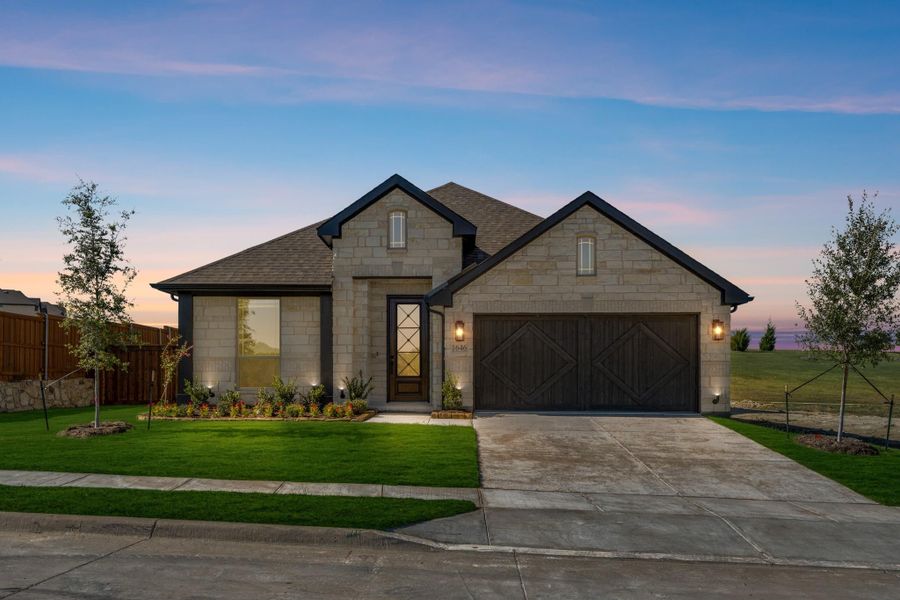 Single-story home with stone exterior, two-car garage, and landscaped front yard at dusk