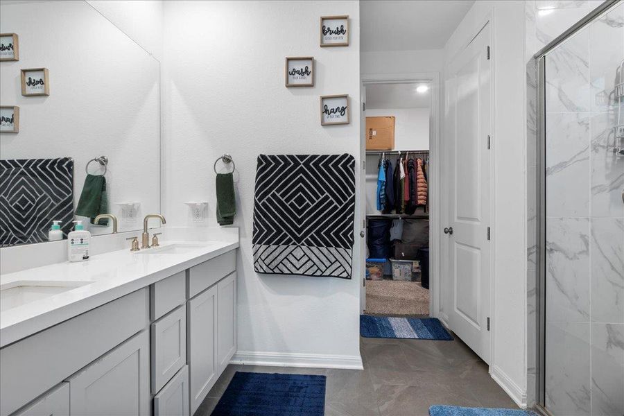 Bathroom featuring double vanity, a marble finish shower, and a walk in closet