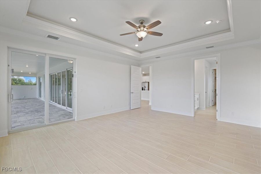 Empty room with ornamental molding, recessed lighting, ceiling fan, a raised ceiling, and wood tiled floors