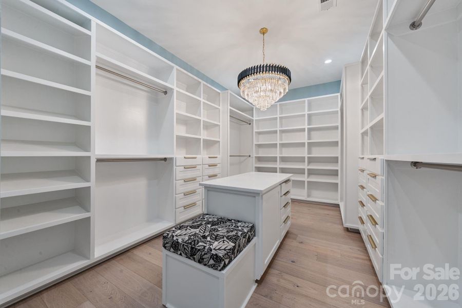 Custom walk-in closet with a statement chandelier and quartz island
