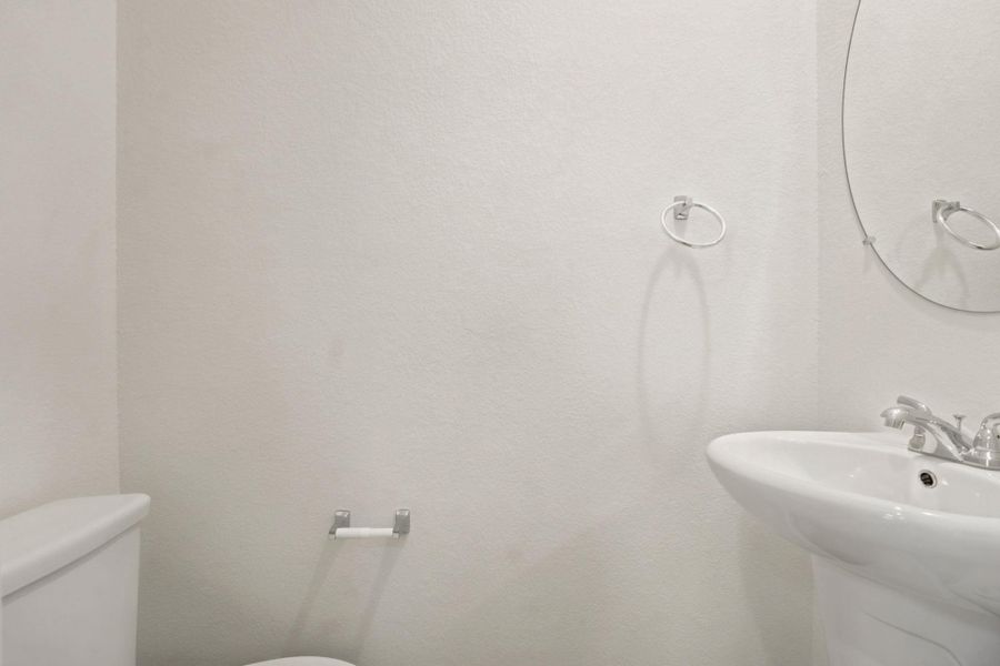 Minimalist pedestal sink pairing seamlessly with neutral textured walls in this half bath.