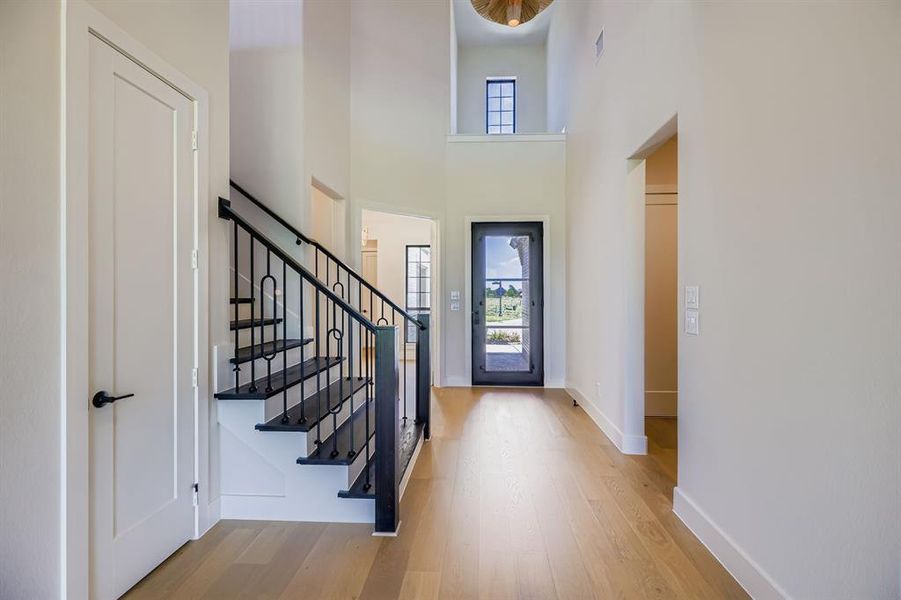 Foyer with wood finished floors, stairs, and a high ceiling