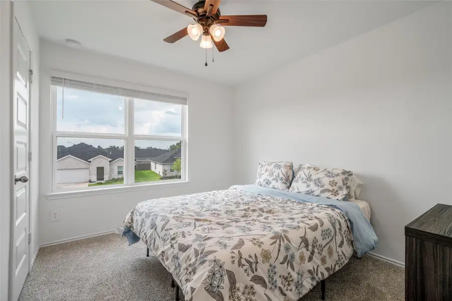 This charming bedroom boasts a large window with privacy blinds, plush carpet, and a ceiling fan, creating a comfortable and serene retreat. This charming bedroom boasts a large window with privacy blinds, plush carpet, and a ceiling fan, creating a comfortable and serene retreat.