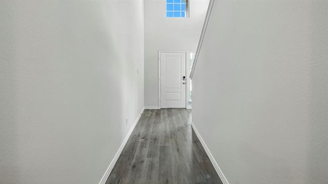 Hallway with a towering ceiling and dark wood-style floors Hallway with a towering ceiling and dark wood-style floors