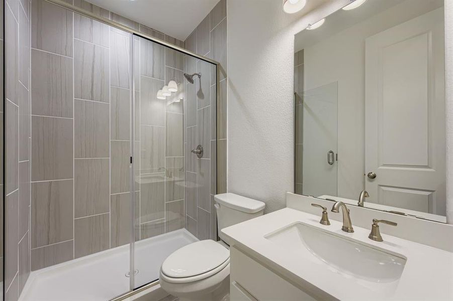 Full bathroom featuring vanity, a textured wall, and a shower stall Full bathroom featuring vanity, a textured wall, and a shower stall