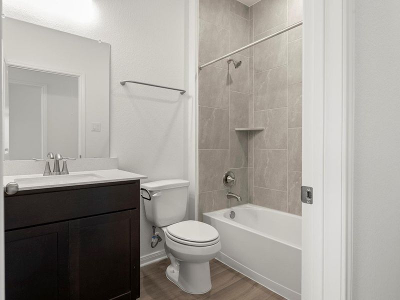 A well-appointed bath features a tiled shower surround and a practical vanity.