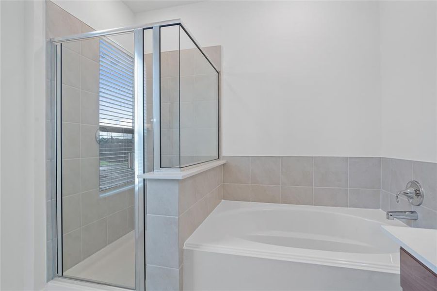 This primary bathroom is definitely move-in ready! Featuring a walk-in shower with tile surround, garden tub to soak after a long day, dark stained cabinets with light countertops, spacious walk-in closet with shelving, high ceilings, custom paint, sleek and dark modern finishes.