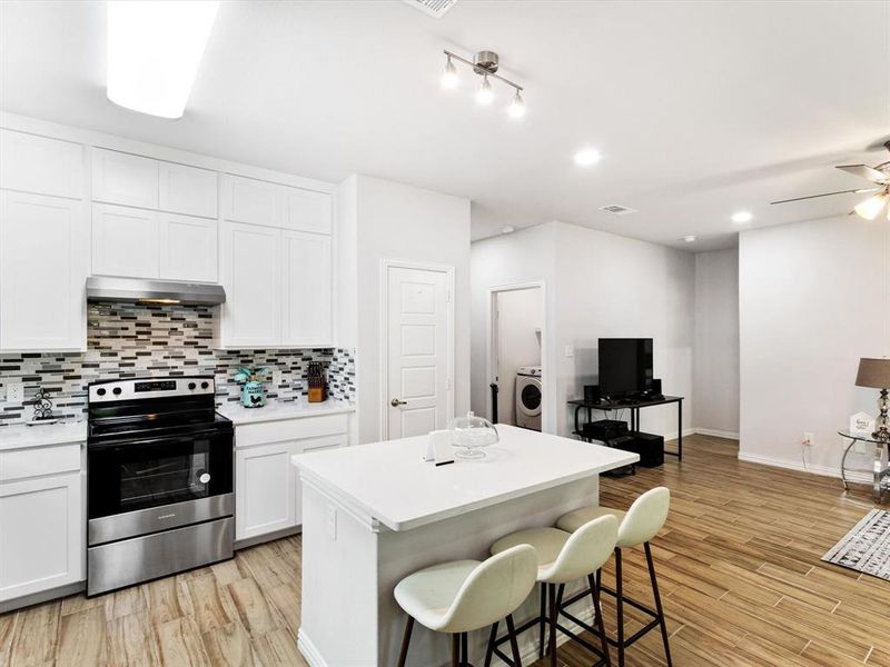 Kitchen featuring white shaker cabinetry, stainless steel oven with range hood, and a mosaic tile backsplash
