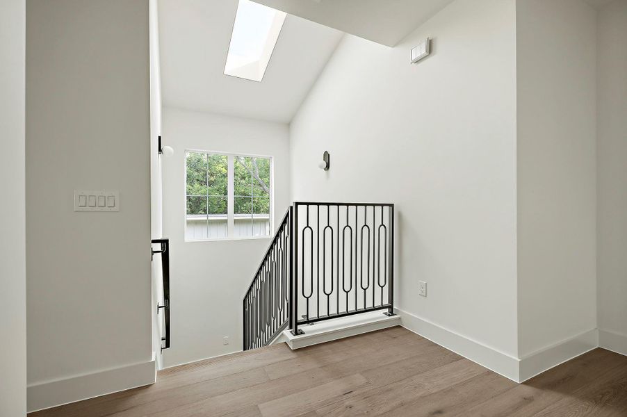 Stairs featuring a skylight, wood finished floors, and baseboards