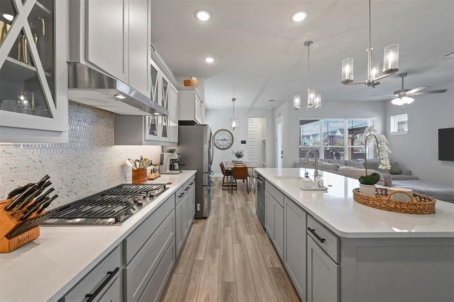 Kitchen featuring appliances with stainless steel finishes, gray cabinetry, exhaust hood, a chandelier, and a ceiling fan Kitchen featuring appliances with stainless steel finishes, gray cabinetry, exhaust hood, a chandelier, and a ceiling fan