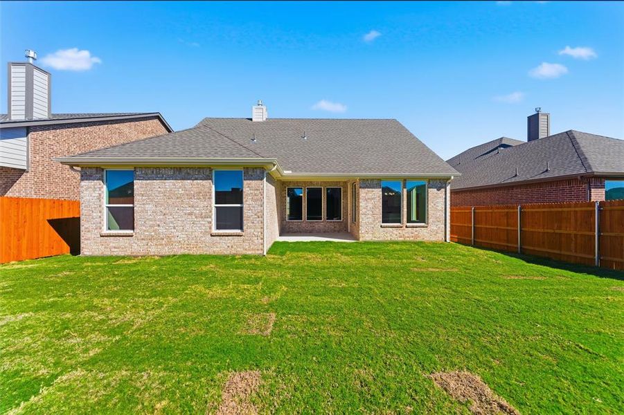 Rear view of property with a fenced backyard, a shingled roof, a patio area, brick siding, and a chimney