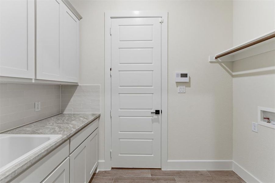 Laundry area featuring white cabinetry, a single basin sink, light grey countertop, and a white subway tile backsplash