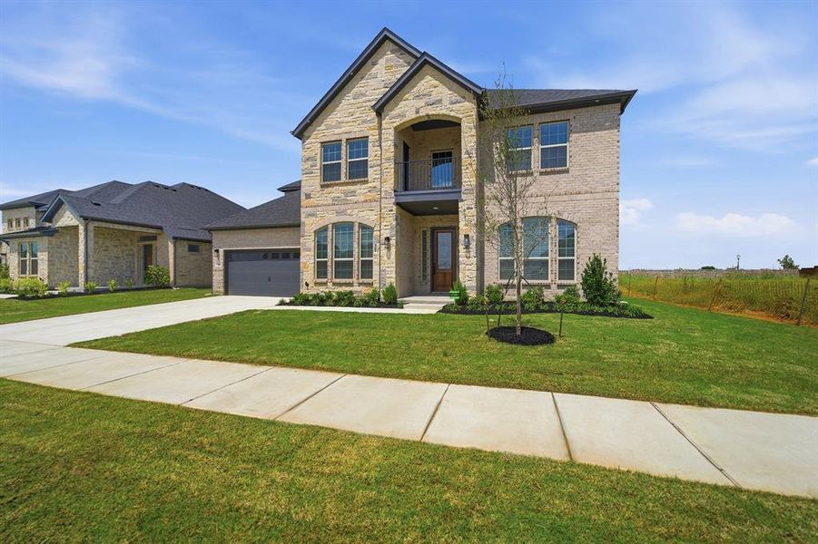 Two-story residence featuring a stone and brick facade, an arched entry, and a second-story balcony