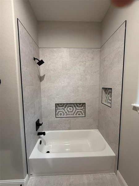 Bathroom with bathing tub / shower combination and baseboards Bathroom with bathing tub / shower combination and baseboards