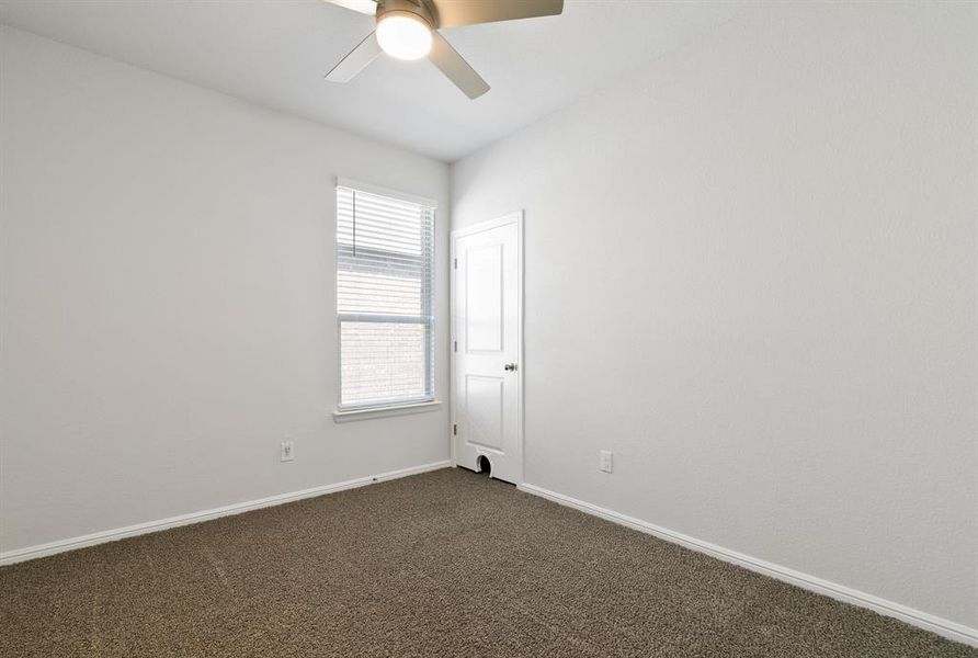 Unfurnished room featuring dark carpet and a ceiling fan