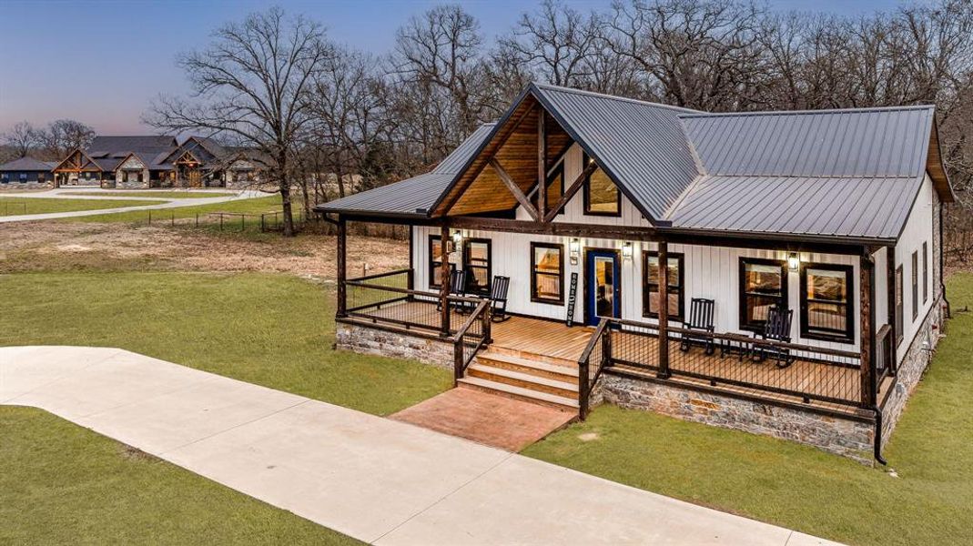 Modern inspired farmhouse with a porch, a lawn, and a metal roof