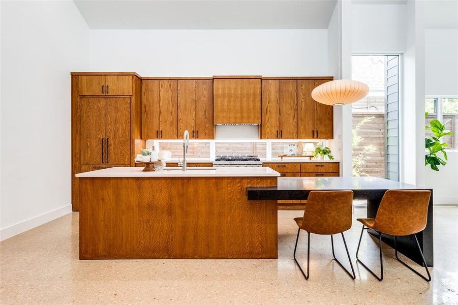 Kitchen featuring a high ceiling, gas stove, and an island with sink