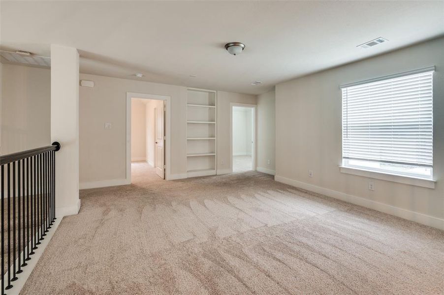 Carpeted spare room with built in features and baseboards Carpeted spare room with built in features and baseboards