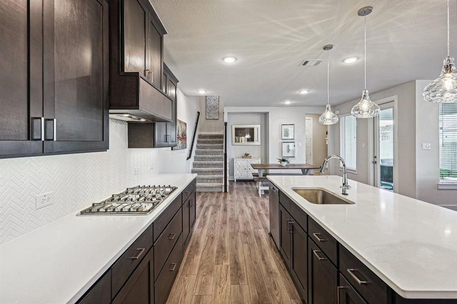 Kitchen featuring sink, stainless steel appliances, decorative light fixtures, and light LVP flooring