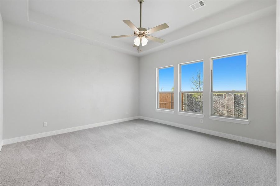 Spare room featuring a raised ceiling, light carpet, and a ceiling fan Spare room featuring a raised ceiling, light carpet, and a ceiling fan