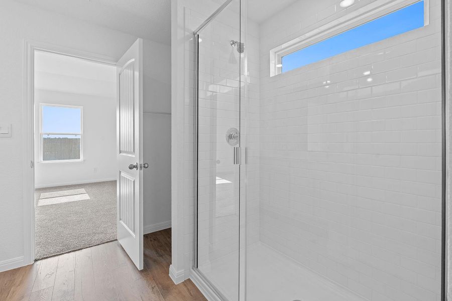 Bathroom featuring light wood finished floors, a shower stall, and light carpet Bathroom featuring light wood finished floors, a shower stall, and light carpet