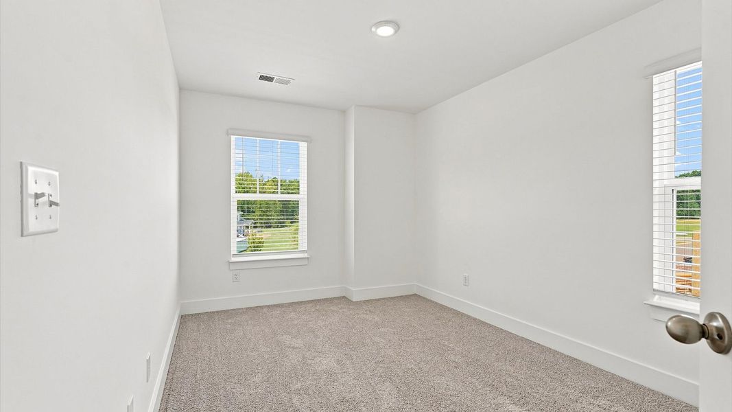 Accomplished bedroom layout with cozy carpet, a spacious walk-in closet, and sun-filled windows Accomplished bedroom layout with cozy carpet, a spacious walk-in closet, and sun-filled windows